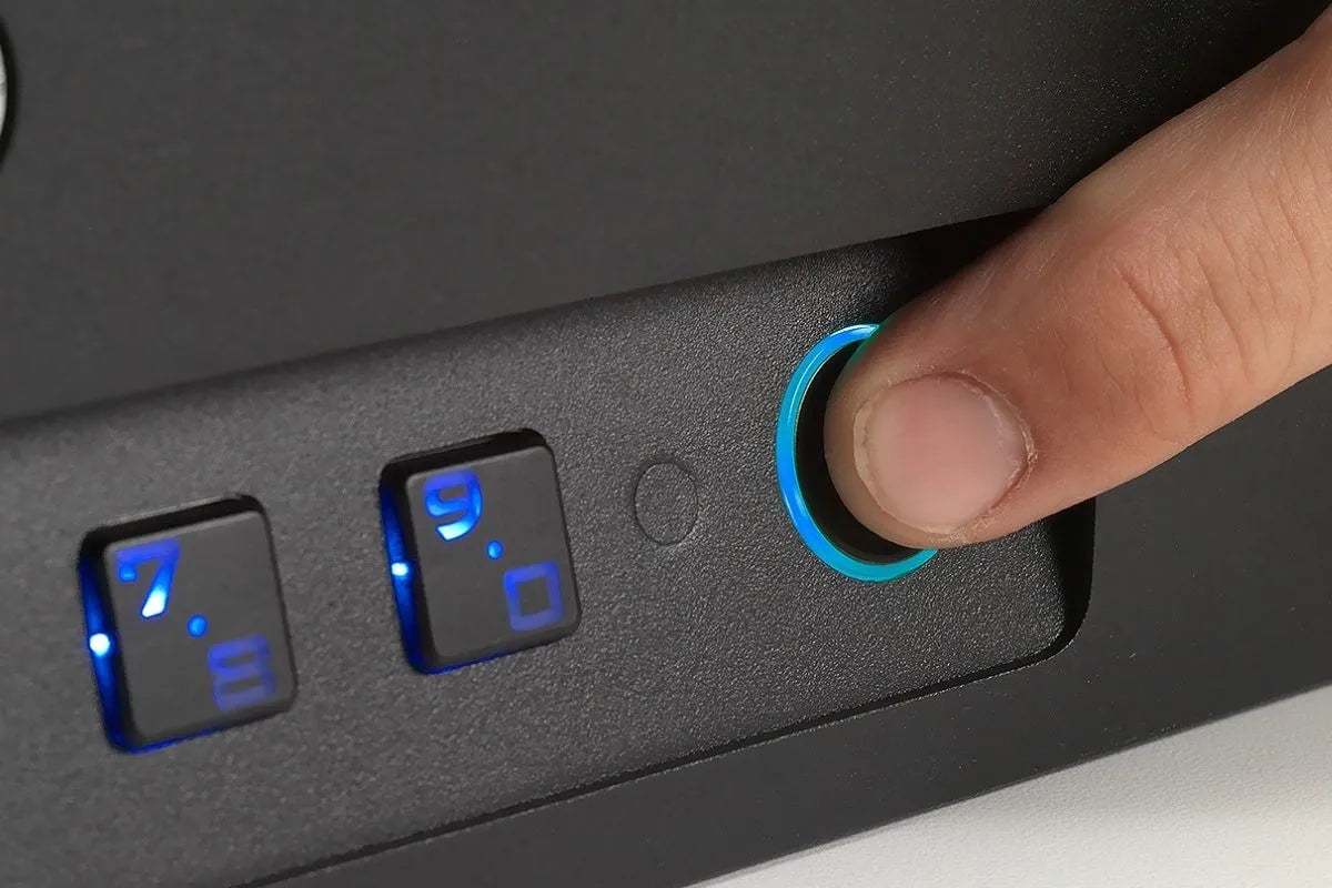 Thumb on the fingerprint reader of a Boosted Safe Elite car safe, keypad lit blue