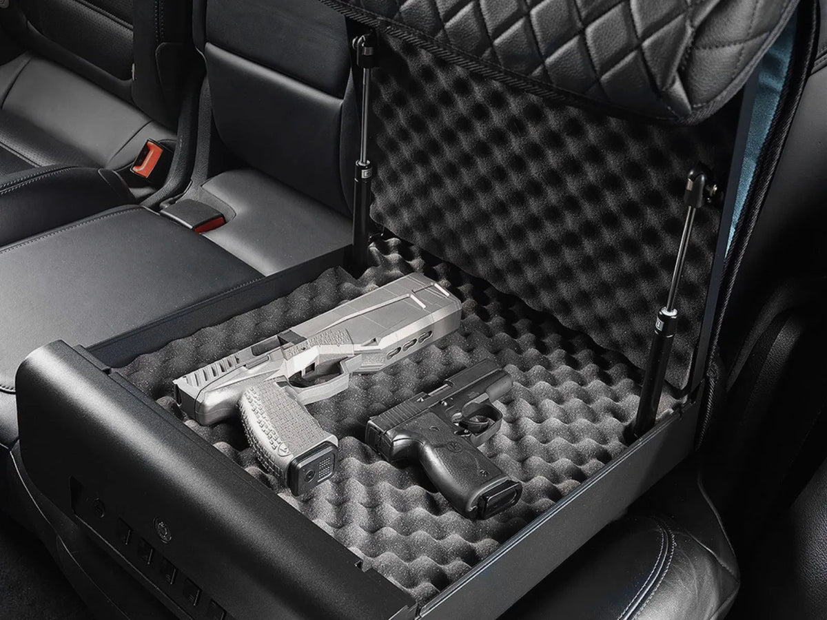 Two unloaded pistols stored in the foam of an open Boosted Safe in a car's back seat