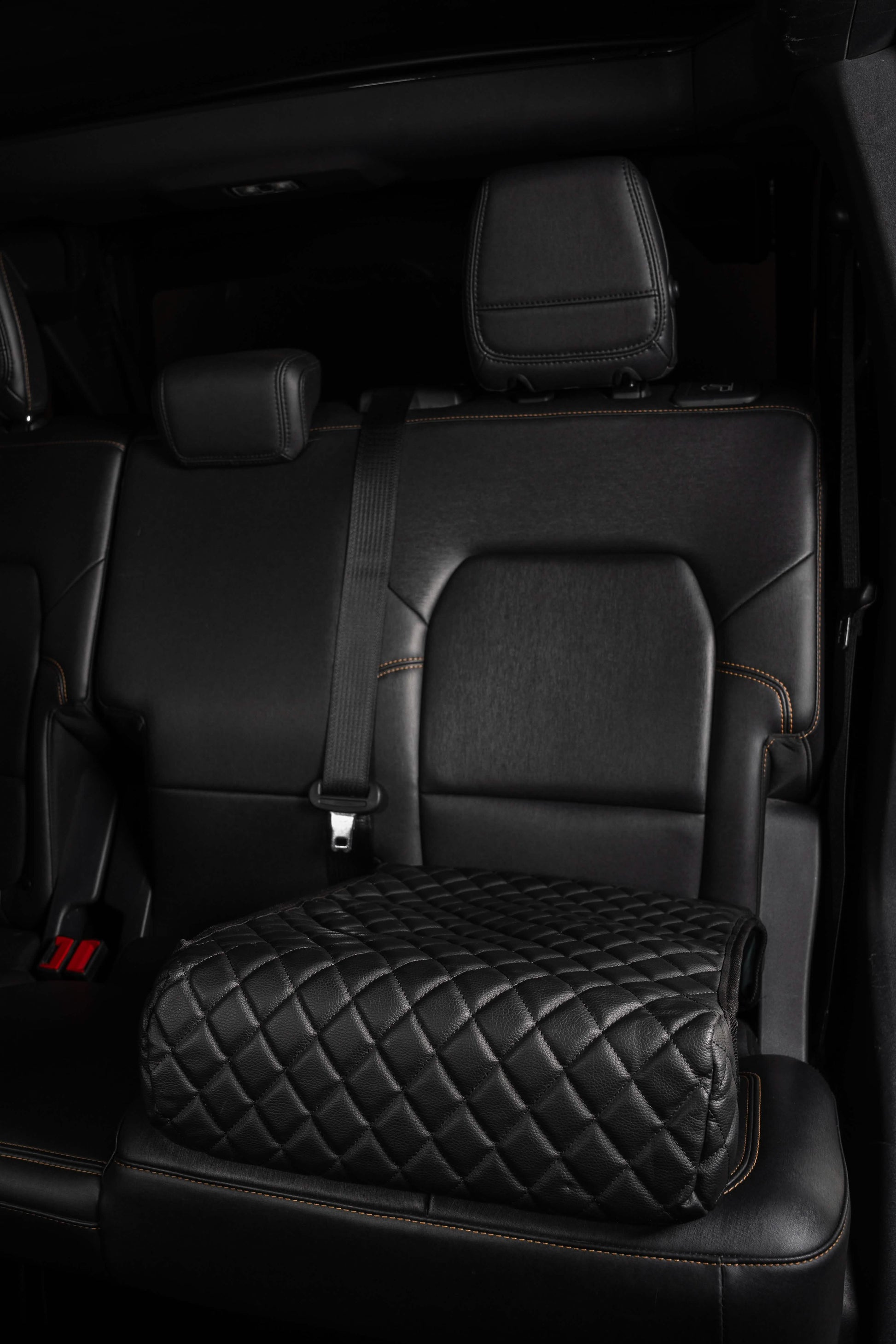 BoostedSafe Elite disguised as a black quilted booster seat cover in a rear SUV seat.
