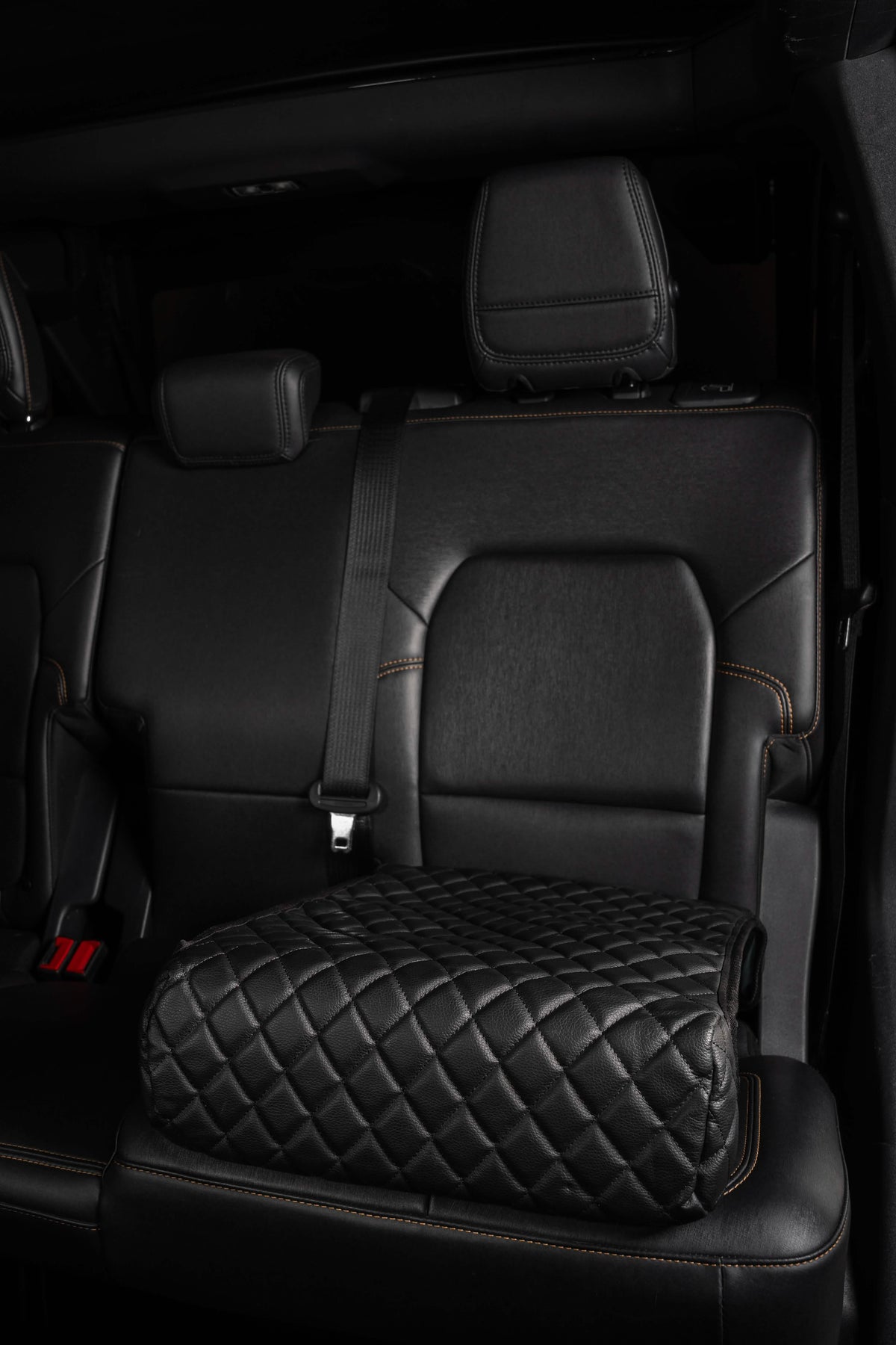 BoostedSafe Elite disguised as a black quilted booster seat cover in a rear SUV seat.