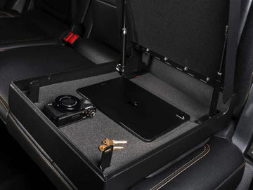 Open BoostedSafe in a rear vehicle seat storing a laptop, camera and keys securely.