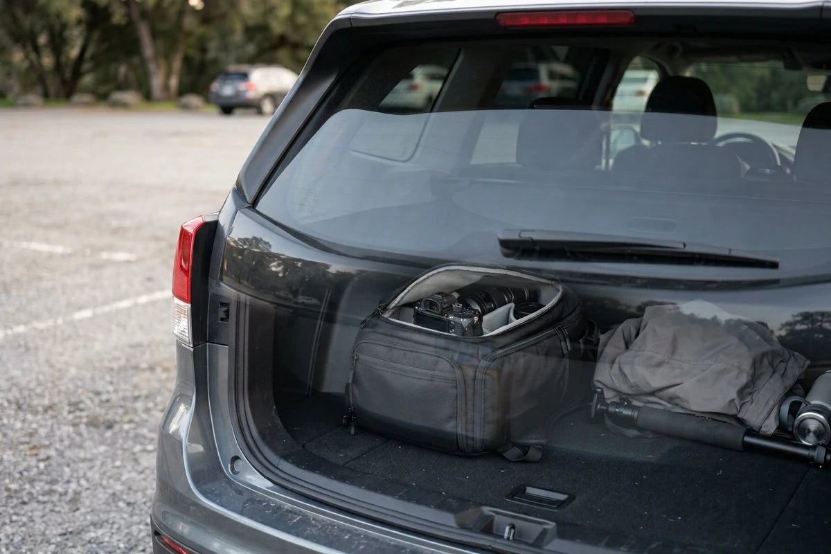 Camera bag and jacket visible through the rear window of an SUV in a parking lot